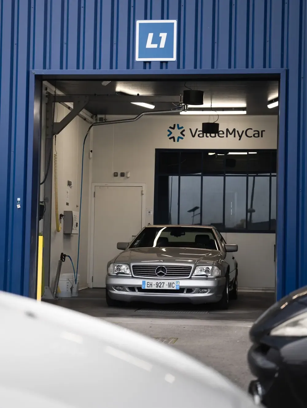 Une Mercedes argentée garée dans le box de lavage L1, sous l’enseigne ValueMyCar
