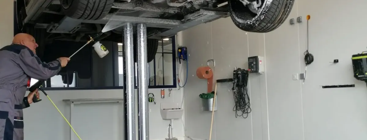 Dessous de caisse d'un véhicule levé sur pont, nettoyé au jet dans un centre ValueMyCar