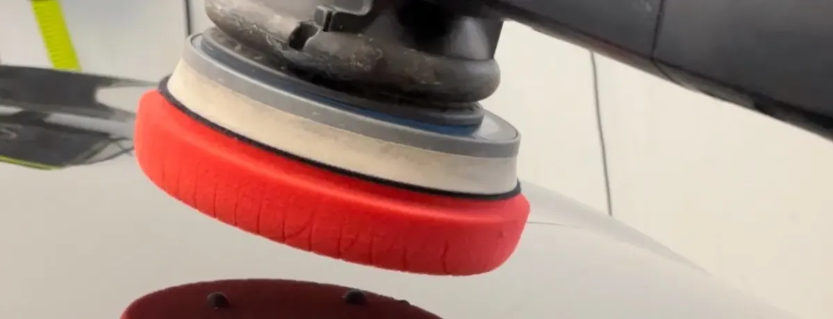 Pose d'un film de protection transparent sur la carrosserie rouge d'une voiture