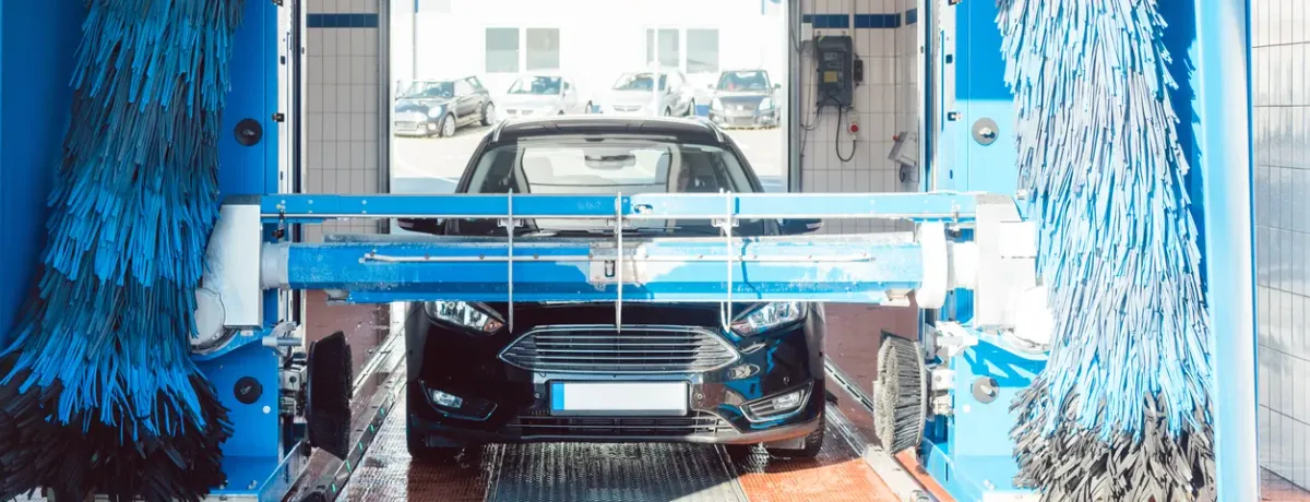 Voiture noire passant dans un portique de lavage automatique à rouleaux