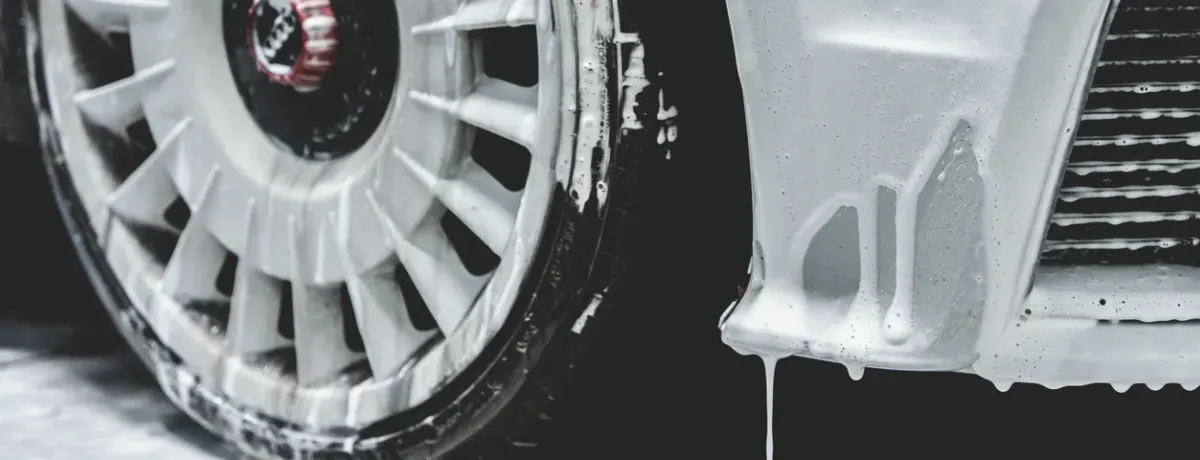 Gros plan sur une jante et un pare-chocs recouverts de mousse de lavage