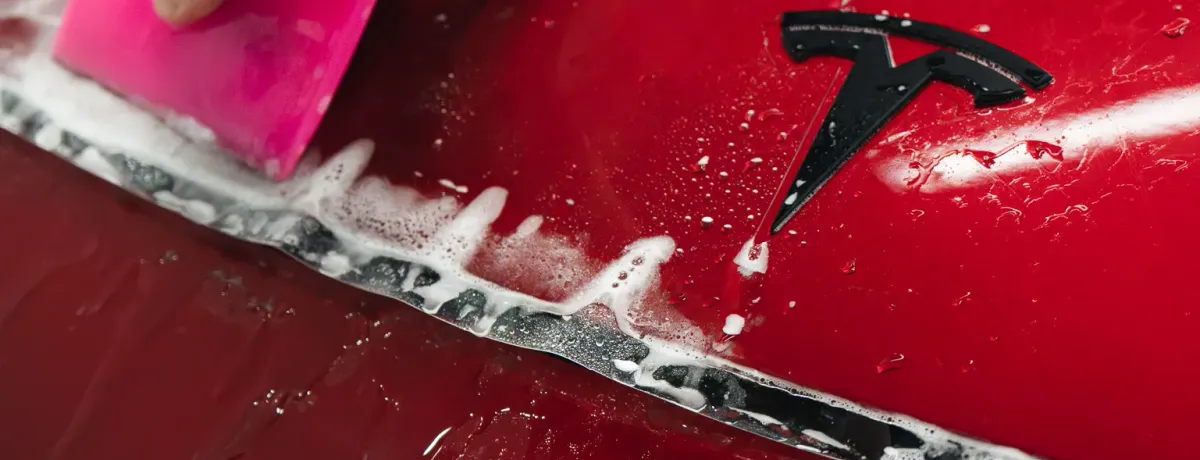 Pose d'un film de protection transparent sur la carrosserie rouge d'une Tesla