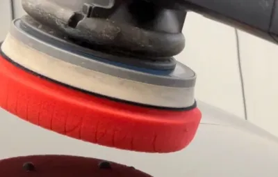 Pose d'un film de protection transparent sur la carrosserie rouge d'une voiture