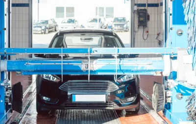 Voiture noire passant dans un portique de lavage automatique à rouleaux