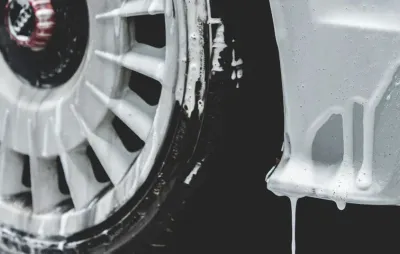 Gros plan sur une jante et un pare-chocs recouverts de mousse de lavage