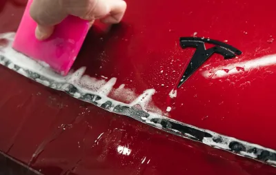 Pose d'un film de protection transparent sur la carrosserie rouge d'une Tesla