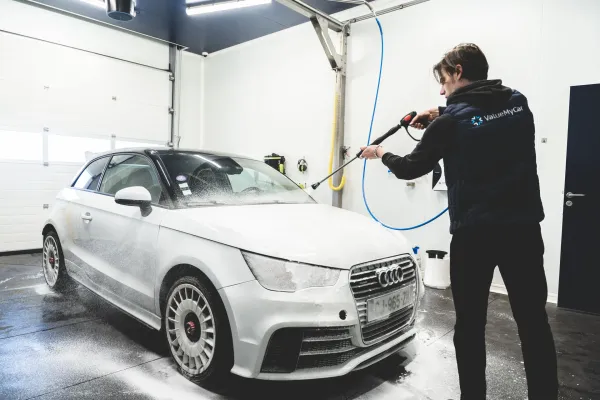 Box lavage chez ValueMyCar avec une voiture se faisant laver avec un jet haute pression